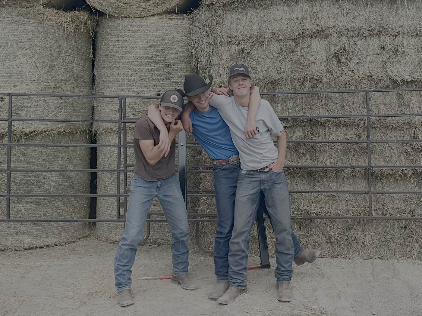 The three-man haying crew in front of stacked bales in the hay shed