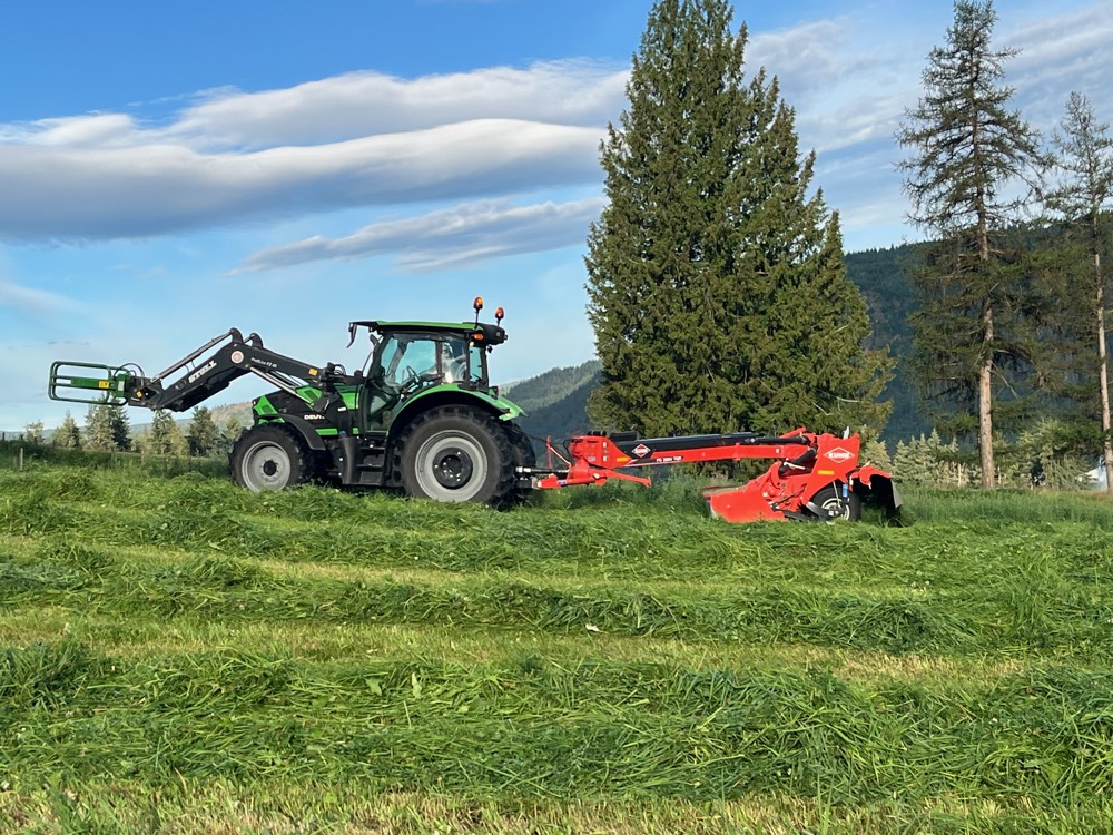 Tractor and disc mower laying down fresh grass